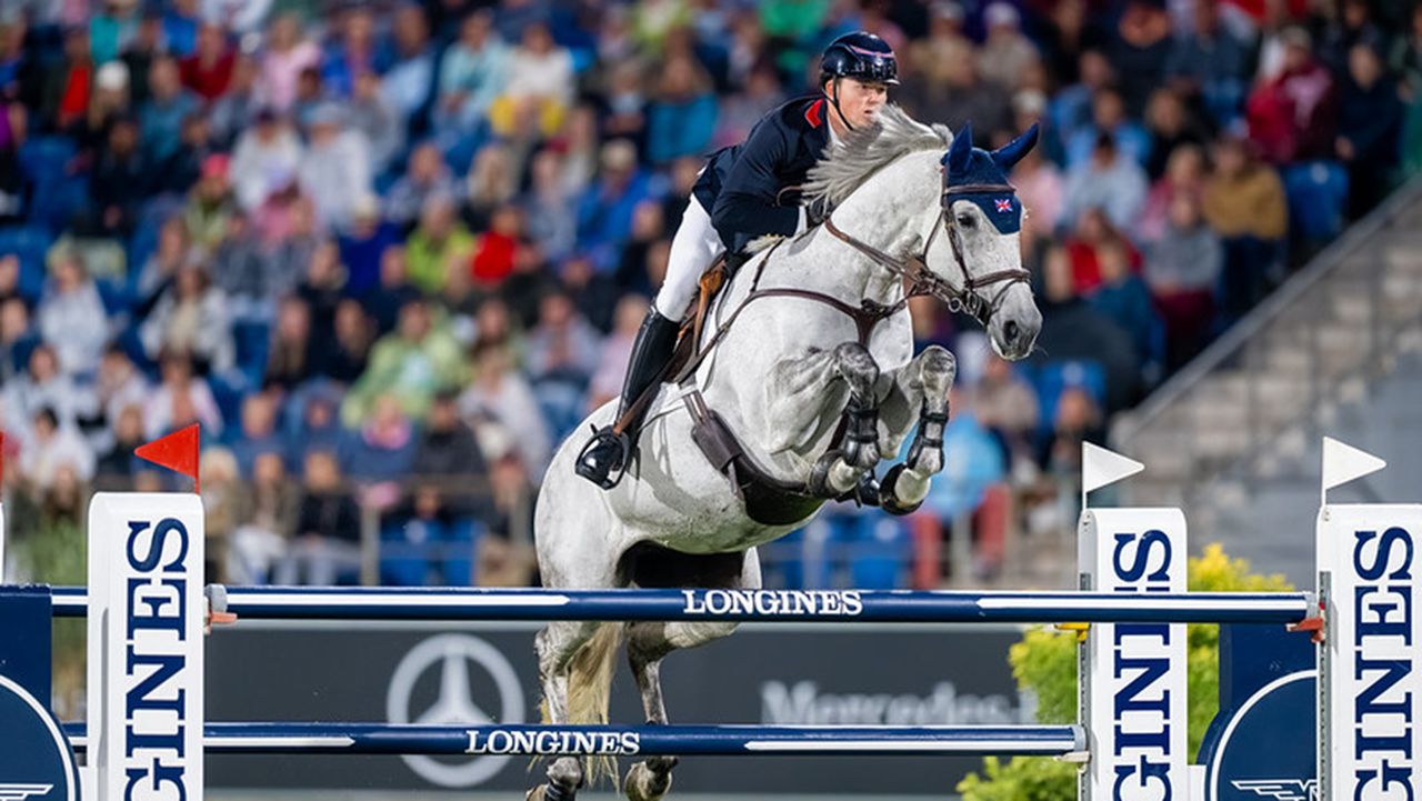 Harry Charles and LT Holst Freda, a grey horse, jump a blue and white fence as they help Britain to bronze at the showjumping World Championships