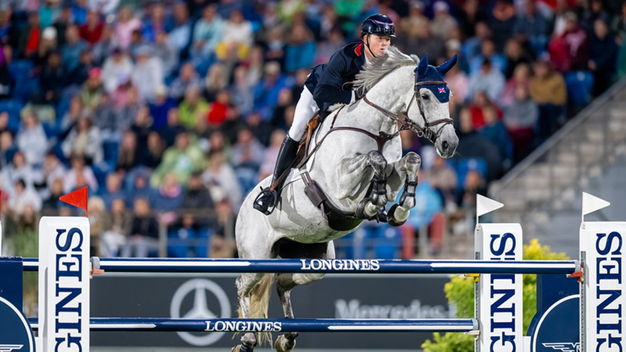 Harry Charles and LT Holst Freda, a grey horse, jump a blue and white fence as they help Britain to bronze at the showjumping World Championships