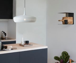 corner of kitchen with white pendant light over kitchen island with blue base and unusual small shelf on wall