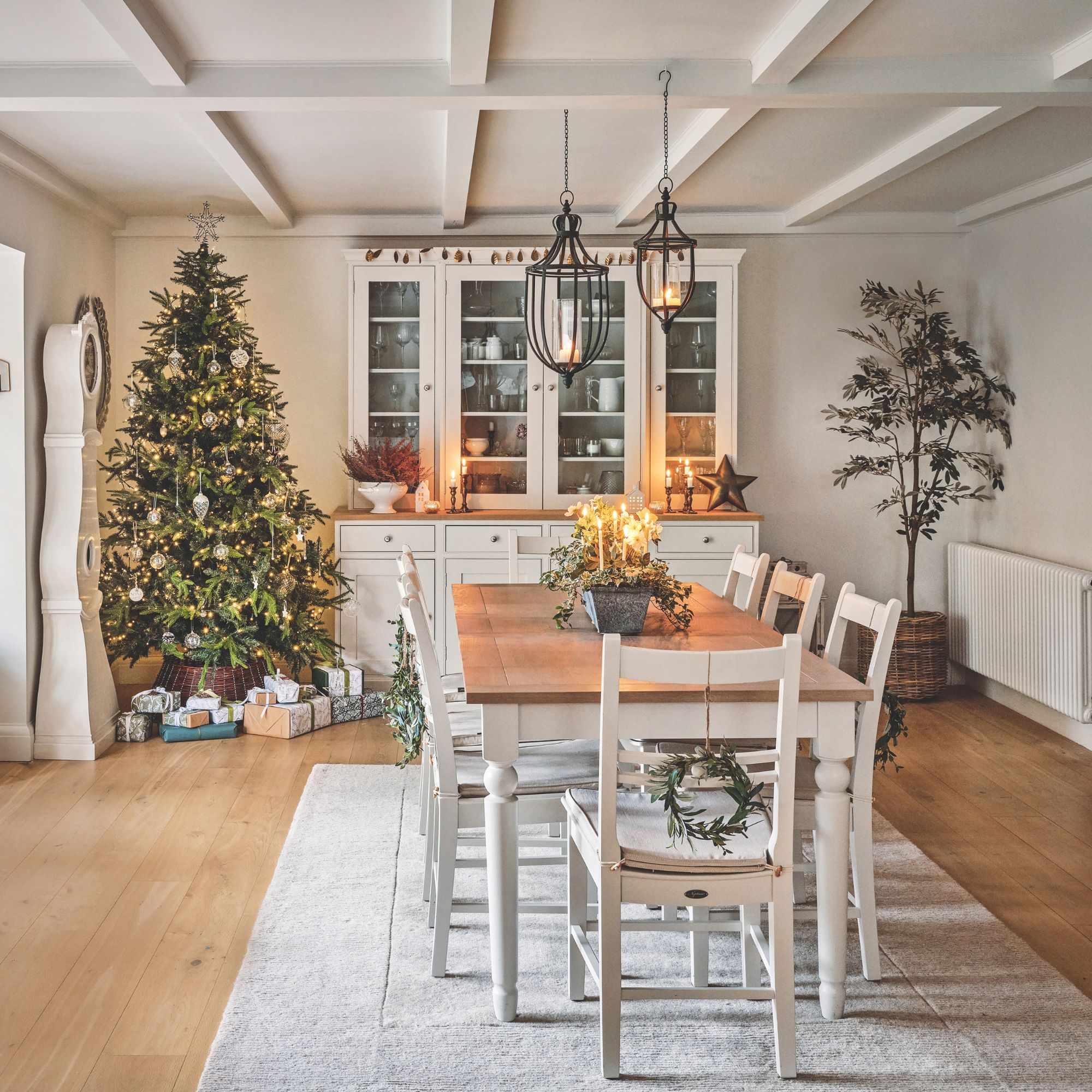 Festive dining room with a wooden dining table and a christmas tree behind it