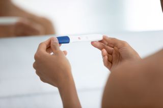 A woman holding a pregnancy test.