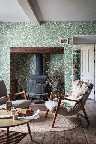 Green botanical wallpaper in a small living room with a antique black fireplace