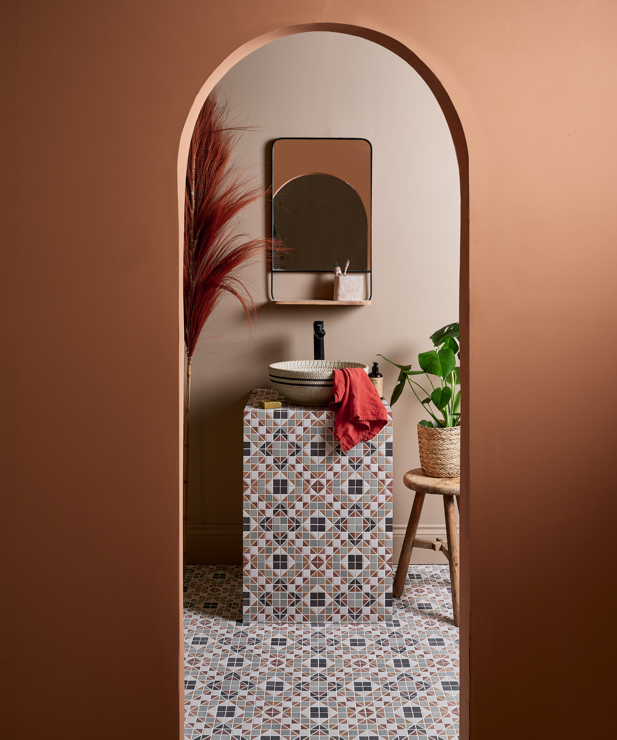 Bathroom with geometric tiles on the floor carried up onto the sink unit