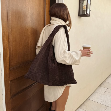 woman wearing turtleneck sweater dress with tall boots and big brown suede bag