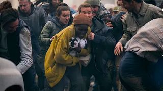 a woman in a panicked crowd holding a cat