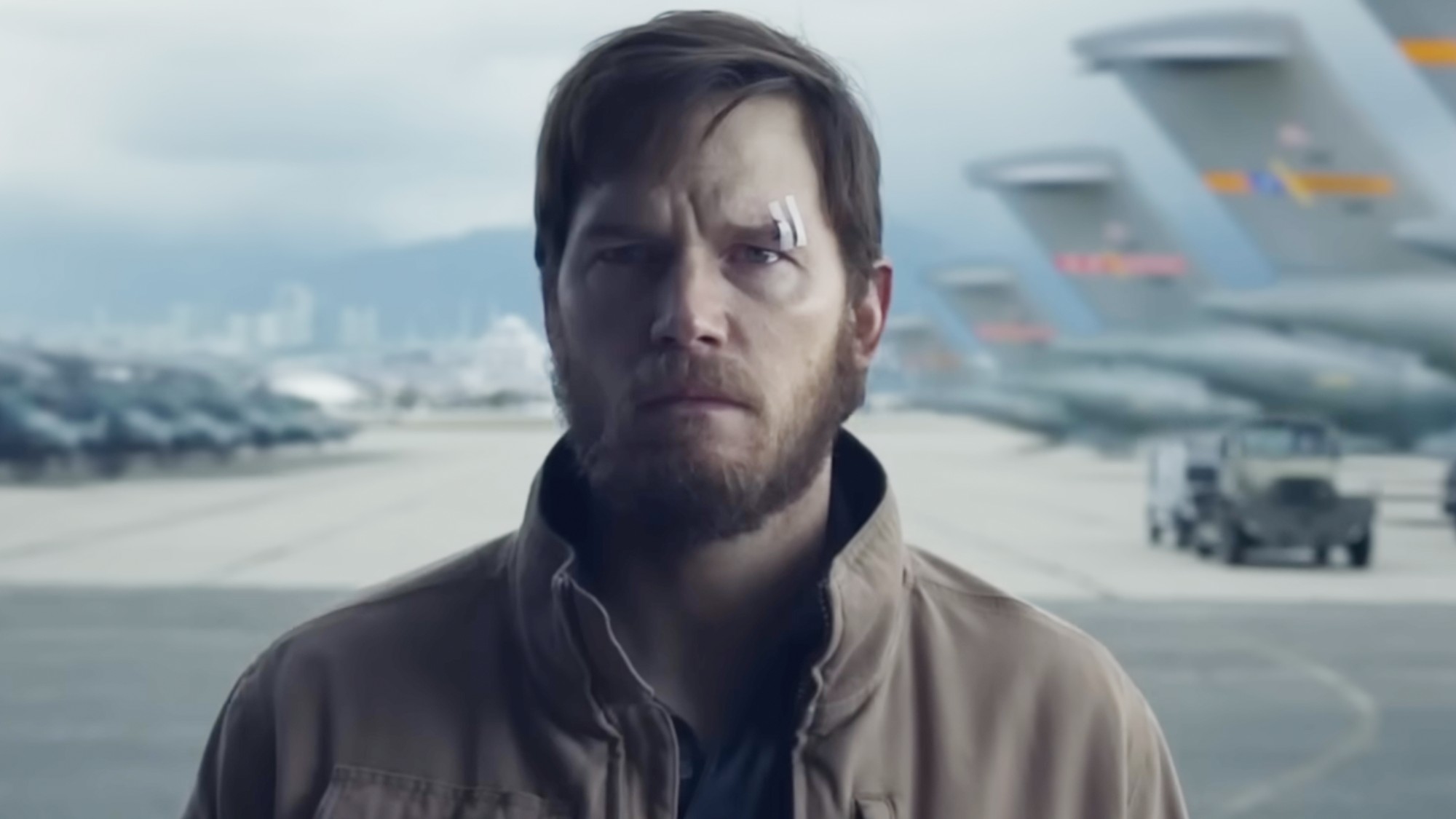 Chris Pratt standing in an airport hanger. 