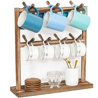 A wooden Puricon 2 tier Mug Holder for Counters with hooks and various mugs and teacups, and a cup of teaspoons