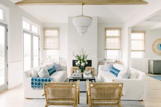 A bright and airy living room with white sofas and a wicker chair