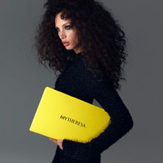 Model holding Mytheresa branded yellow box