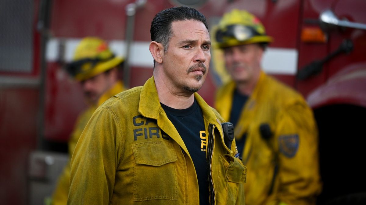 Kevin Alejandro as Manny standing in front of a fire truck in Season 2 of Fire Country.