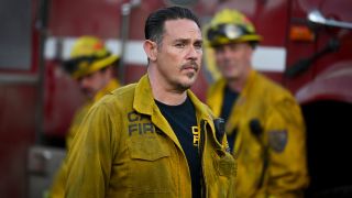 Kevin Alejandro as Manny standing in front of a fire truck in Season 2 of Fire Country.