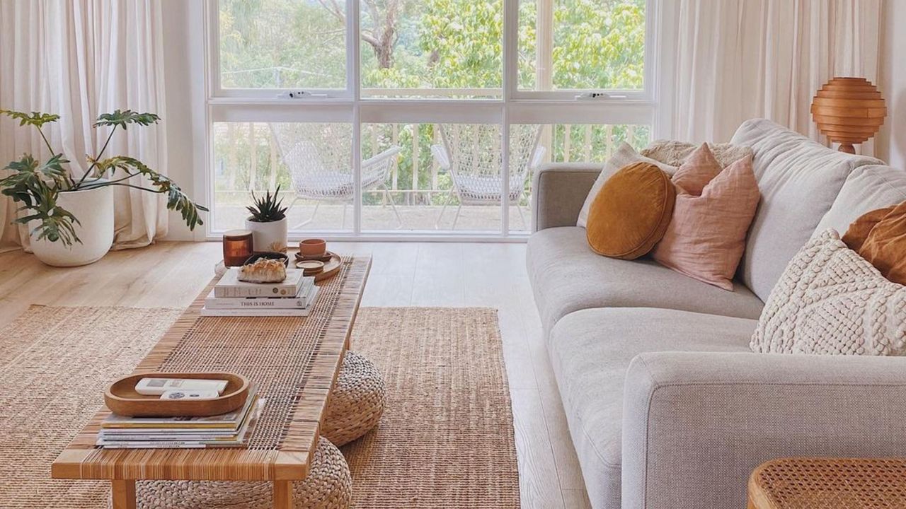 A living room with a gray couch, coffee table, and large windows