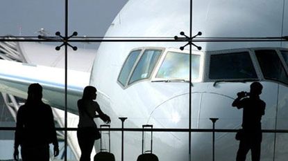 people standing an airport with a plane outside the window