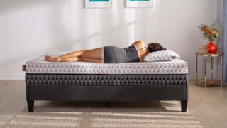 Layla Memory Foam Mattress review: A woman with dark, curly hair lies on her side on the Layla mattress