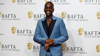 Ncuti Gatwa has his photo taken in a blue and black suit at the BAFTA Scotland Awards 2022.