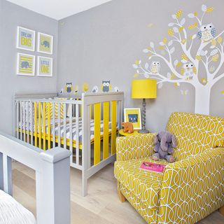 A baby nursery with a cot and yellow armchair