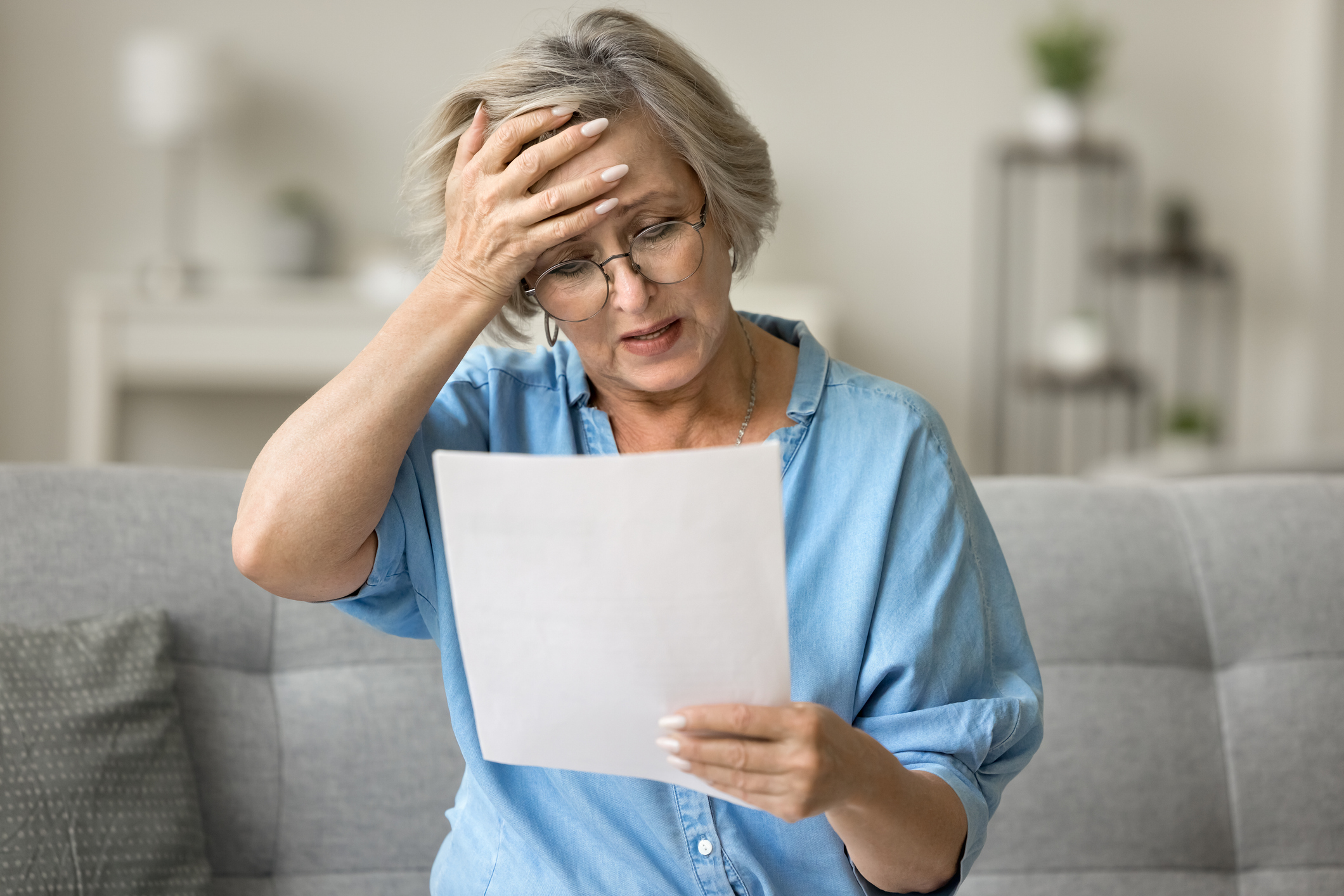 a woman placing a hand to her head while reading a document 