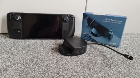 Syntech 6-in-1 Steam Deck Docking Station sitting next to the Steam Deck and packaging for the dock