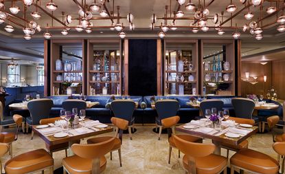 Dining area with taupe leather seating, bronze light fixtures and highlights of blue