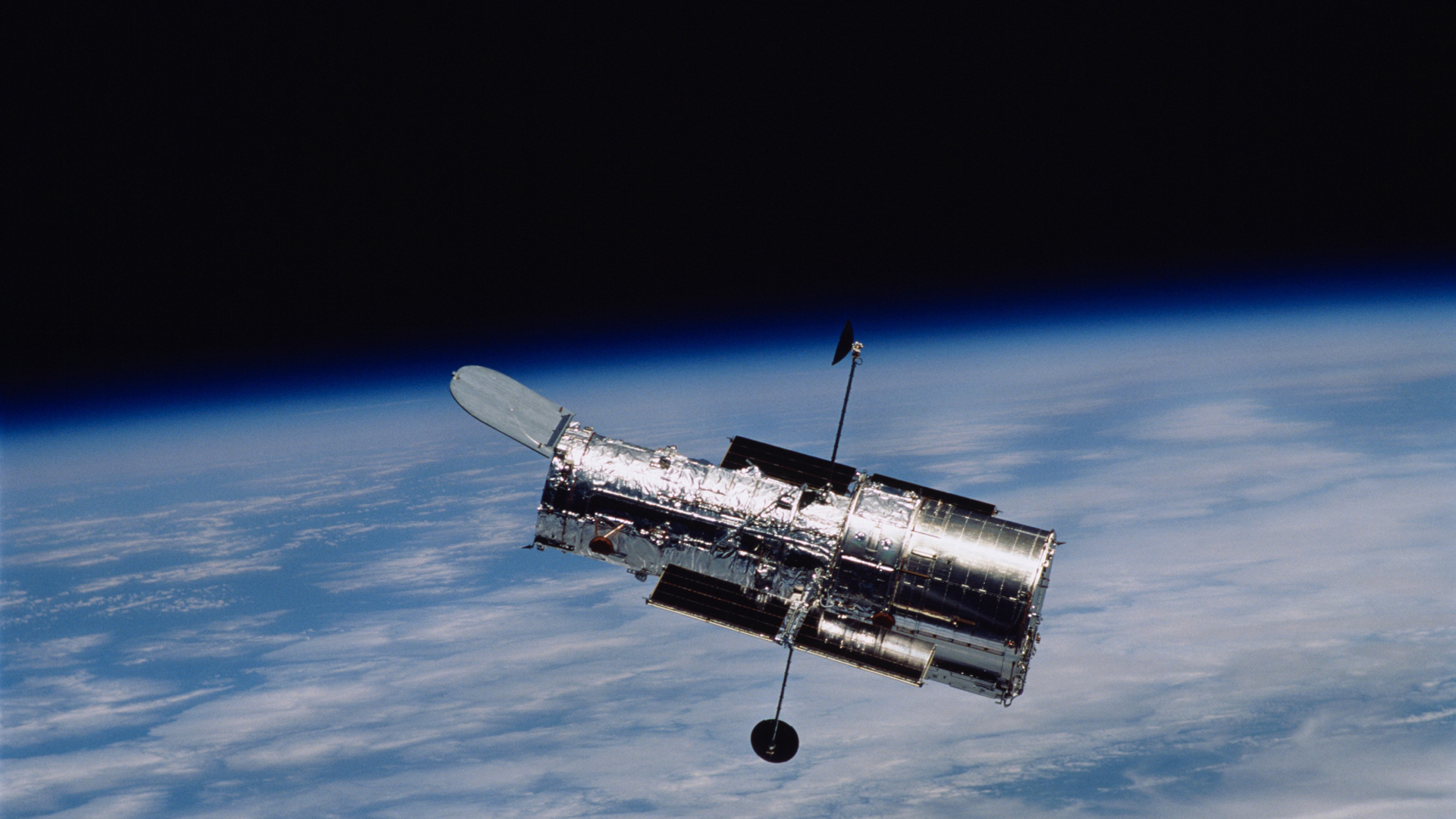 The Hubble Space Telescope flying above Earth pictured below.