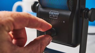 the gain dial of a small retro-inspired microphone with a large RGB sound capsule is photographed against a blue background