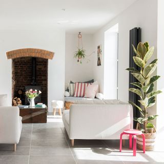 White living room with tiled floor, white sofas, fireplace and plants