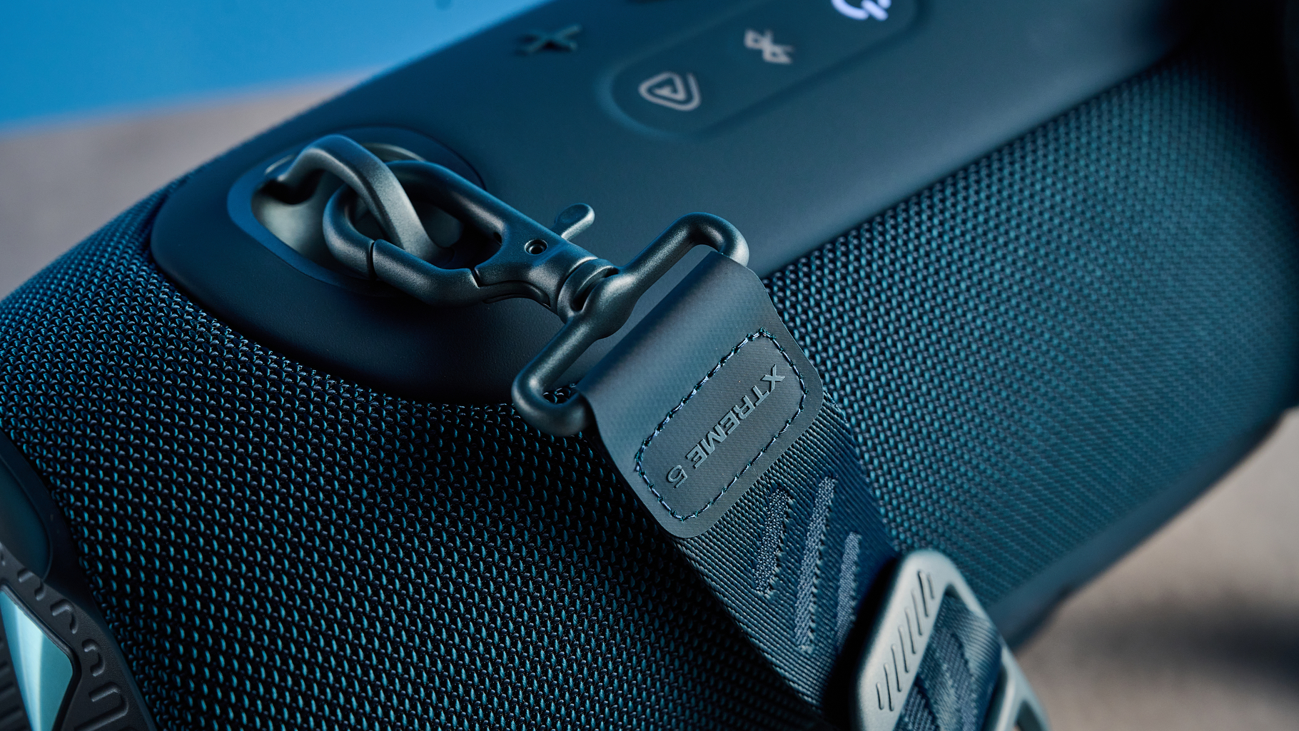 the JBL Xtreme 5 bluetooth speaker in blue shown with the rugged carry strap and buttons