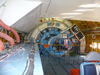 A view looking tailward through the cabin of NASA's SOFIA flying observatory. At the back, two science instruments jut from a bulkhead. The instruments are attached to SOFIA's 17-ton telescope, which sits on the other side of the bulkhead.
