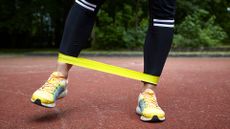 Woman doing crab walk exercise, stepping sideways with resistance band wrapped around trainers