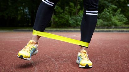Woman doing crab walk exercise, stepping sideways with resistance band wrapped around trainers