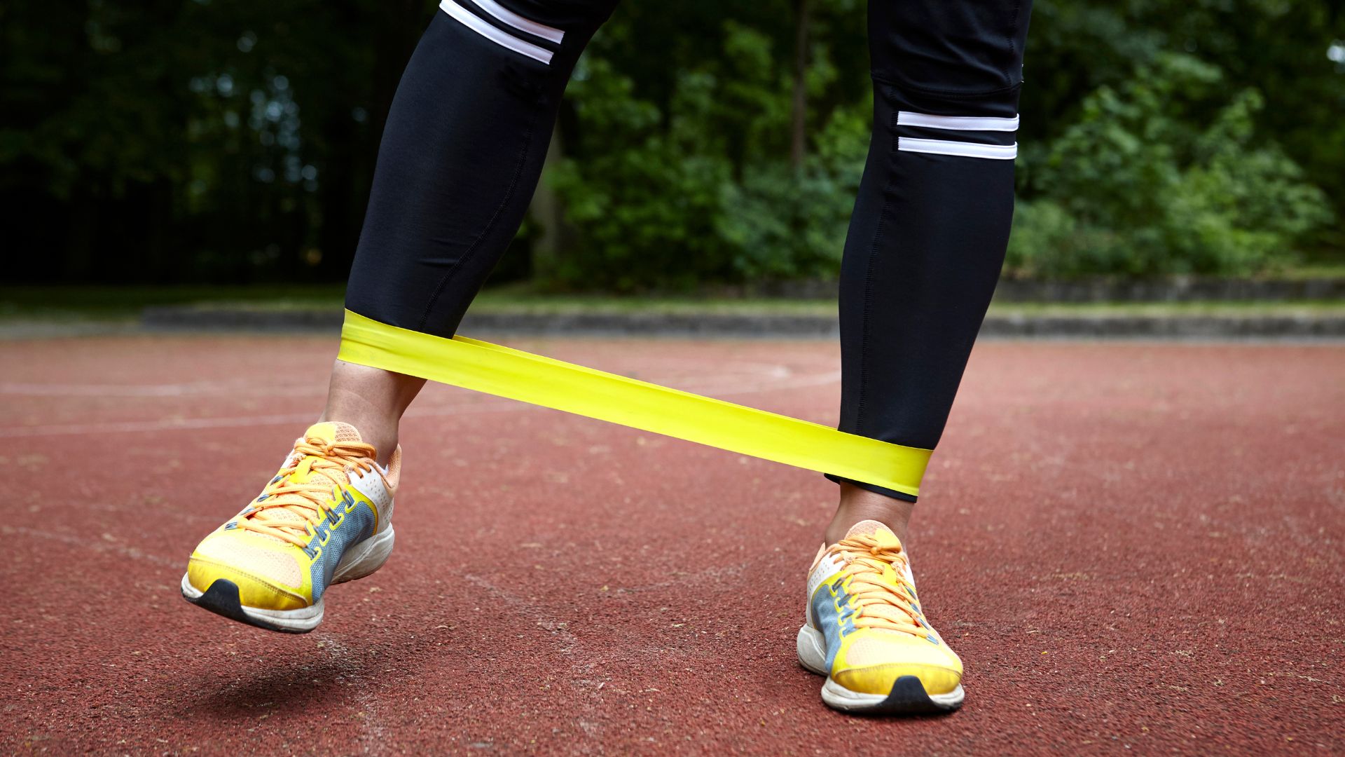 Woman doing crab walk exercise, stepping sideways with resistance band wrapped around trainers
