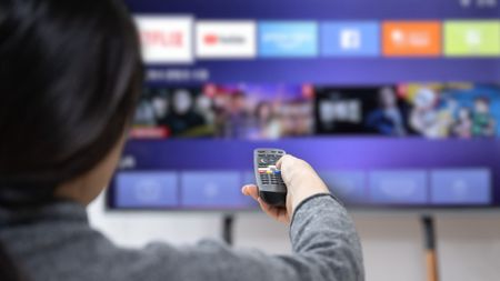 woman using remote control on smart tv