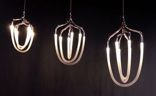 Three hanging lamps with silver frames and thin looping globes.