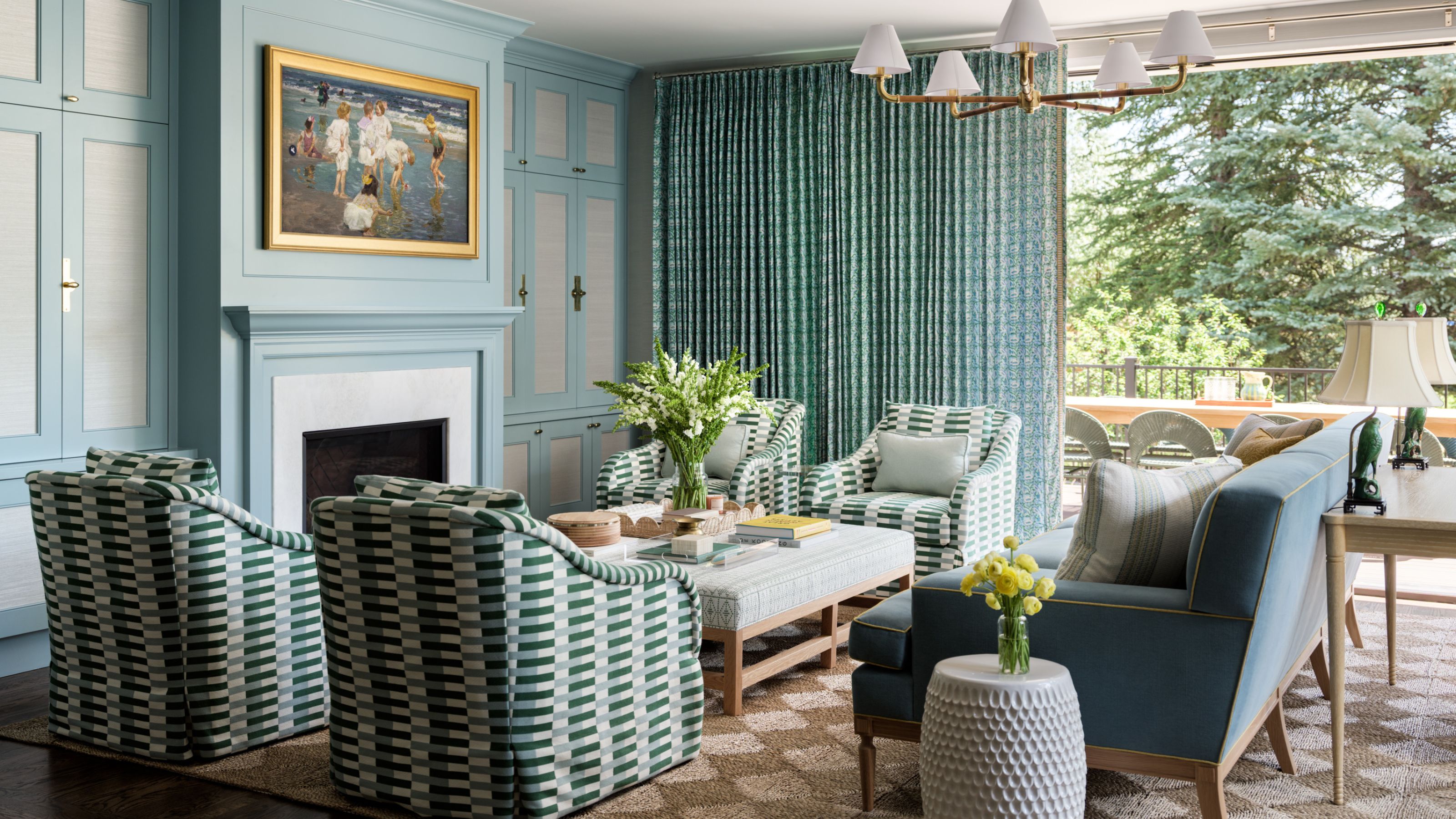 a blue painted living room with large patio doors open to outdoors. A seagrass rug sits underneath patterned armchairs and a blue couch