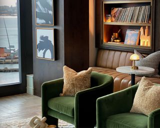 Lauren Jayne Design's living room with green chairs, a leather bench and a vinyl collection