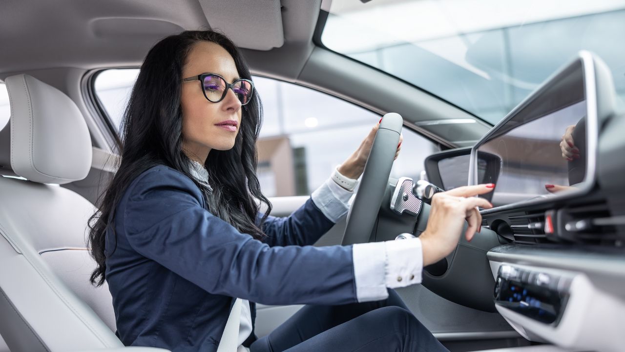 A woman uses the touchscreen in her car.