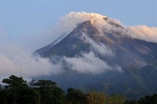 Merapi volcano spews smoke, taken from Umbul Harjo village in Sleman, Yogyakarta on early October 26, 2010. Indonesia ordered thousands of people to evacuate from around Mount Merapi on October 25 as it raised the alert for its most active volcano to red, warning of a possible imminent eruption.