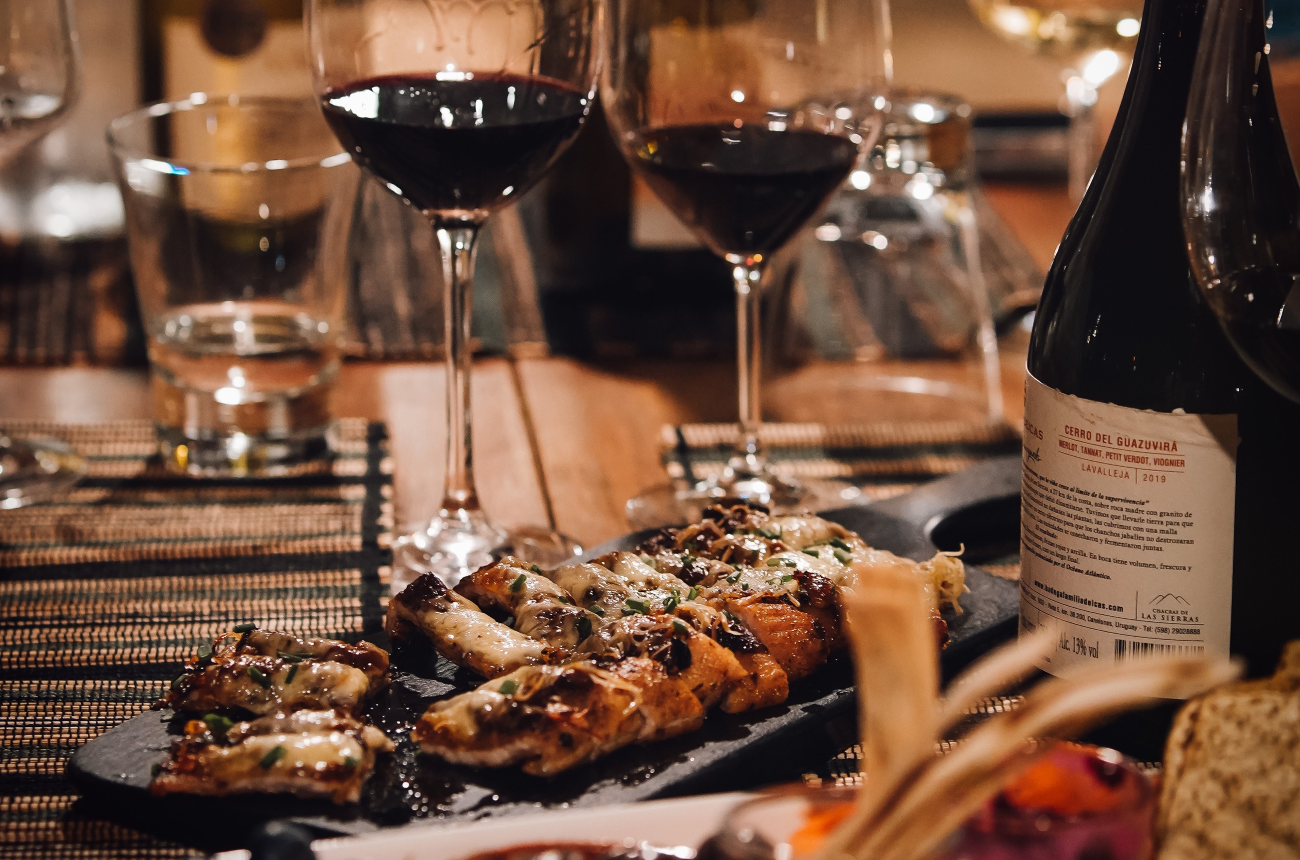 Close-up shot of a table with meat dishes and glasses of red wine