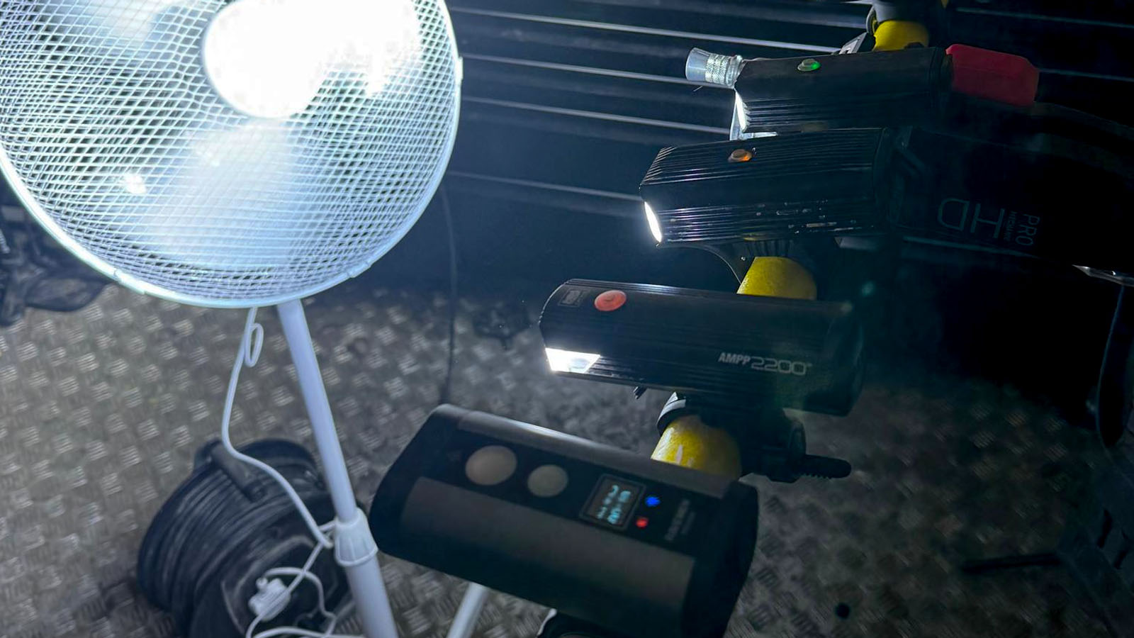 A selection of MTB front lights attached to a bar in a workshop