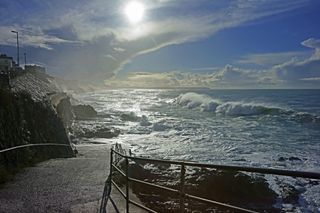 A very misty and stormy winter scene showing dramatic cloud formation at sunrise of a very turbulant sea at Porthleven looking towards Loe Bar, Cornwall, United Kingdom, England.