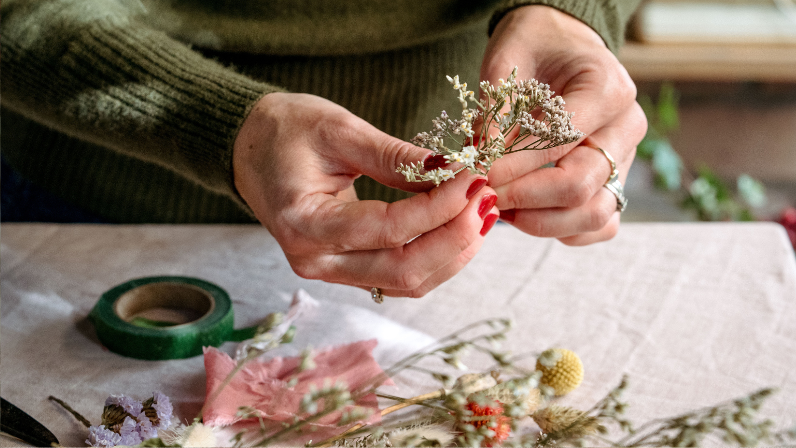 Hands holding two dried stems of white limonium, ready to arrange