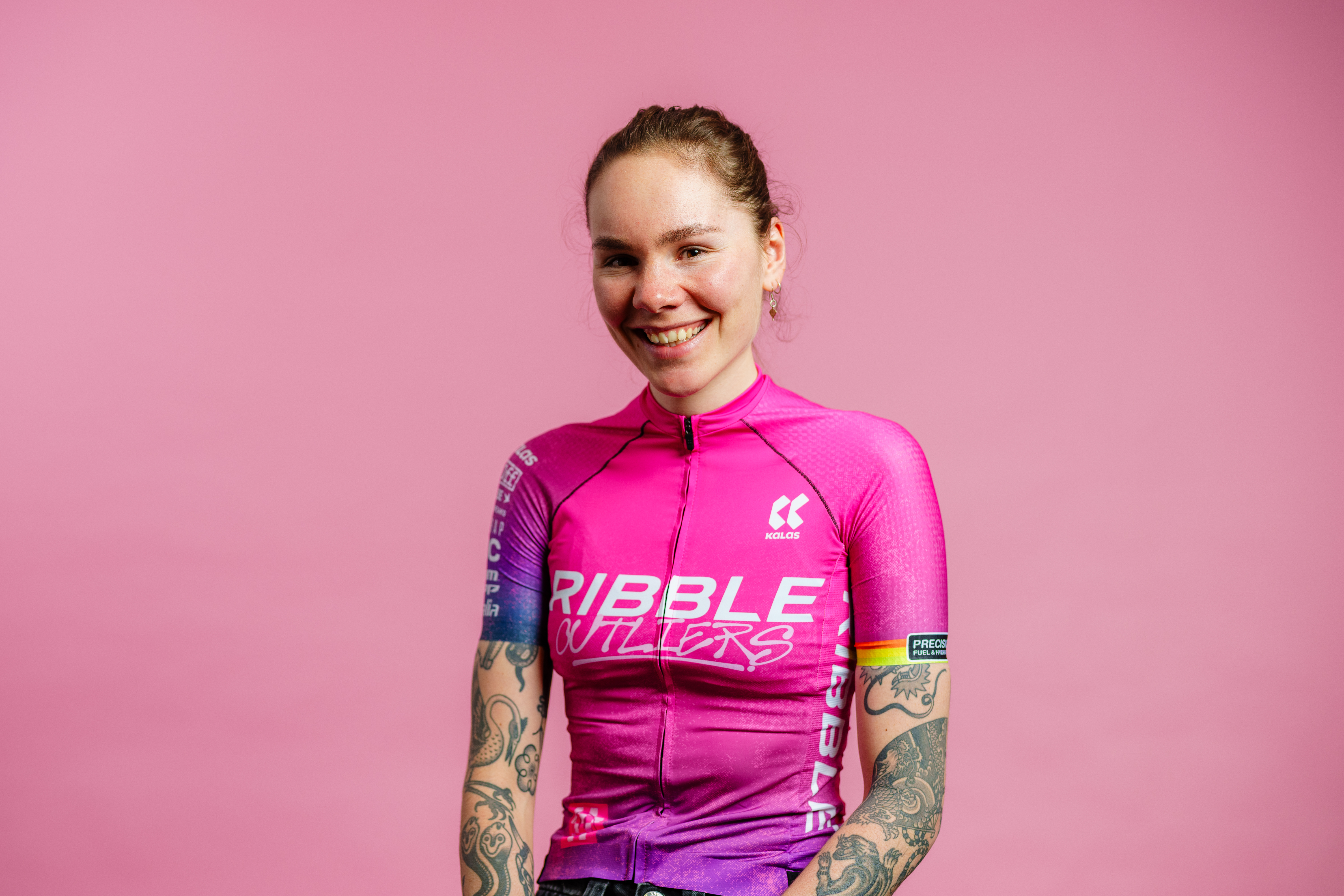Portrait of a woman in a pink and purple jersey against a pink background