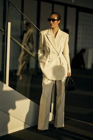 Woman wearing all-whtie suit with black bag.