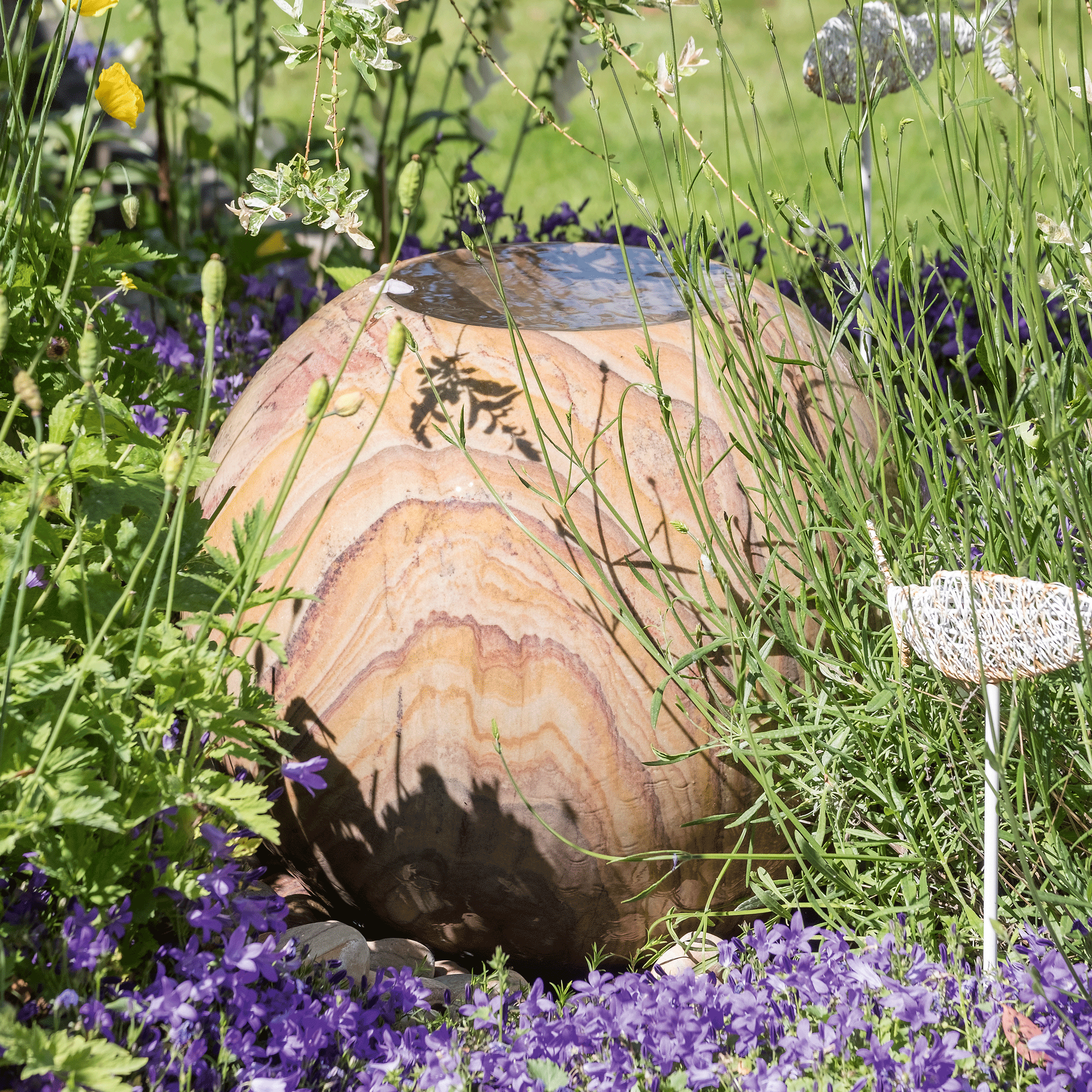 a garden with a wooden water feature surrounded by flowers