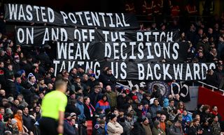 Crystal Palace fans hold a banner in protest during the Premier League match between Arsenal FC and Crystal Palace at Emirates Stadium on January 20, 2024 in London, England.