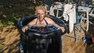 Samantha Priestley settling into an ice bath in her back garden surrounded by towels