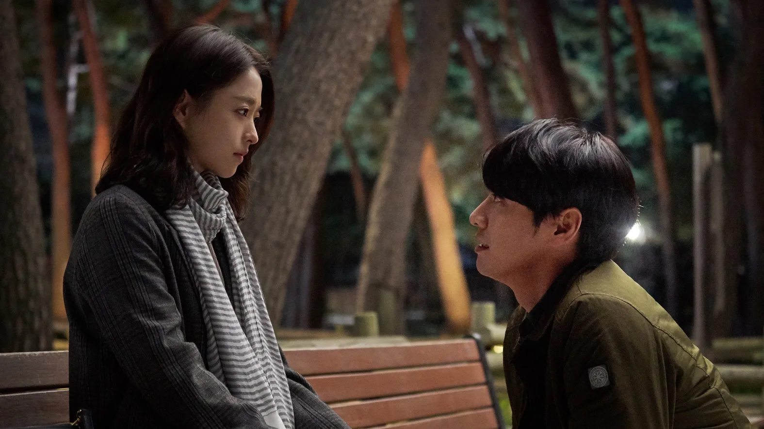 A still from the Korean romance movie 'On Your Wedding Day' of a girl in a scarf sitting on a bench and a man proposing to her