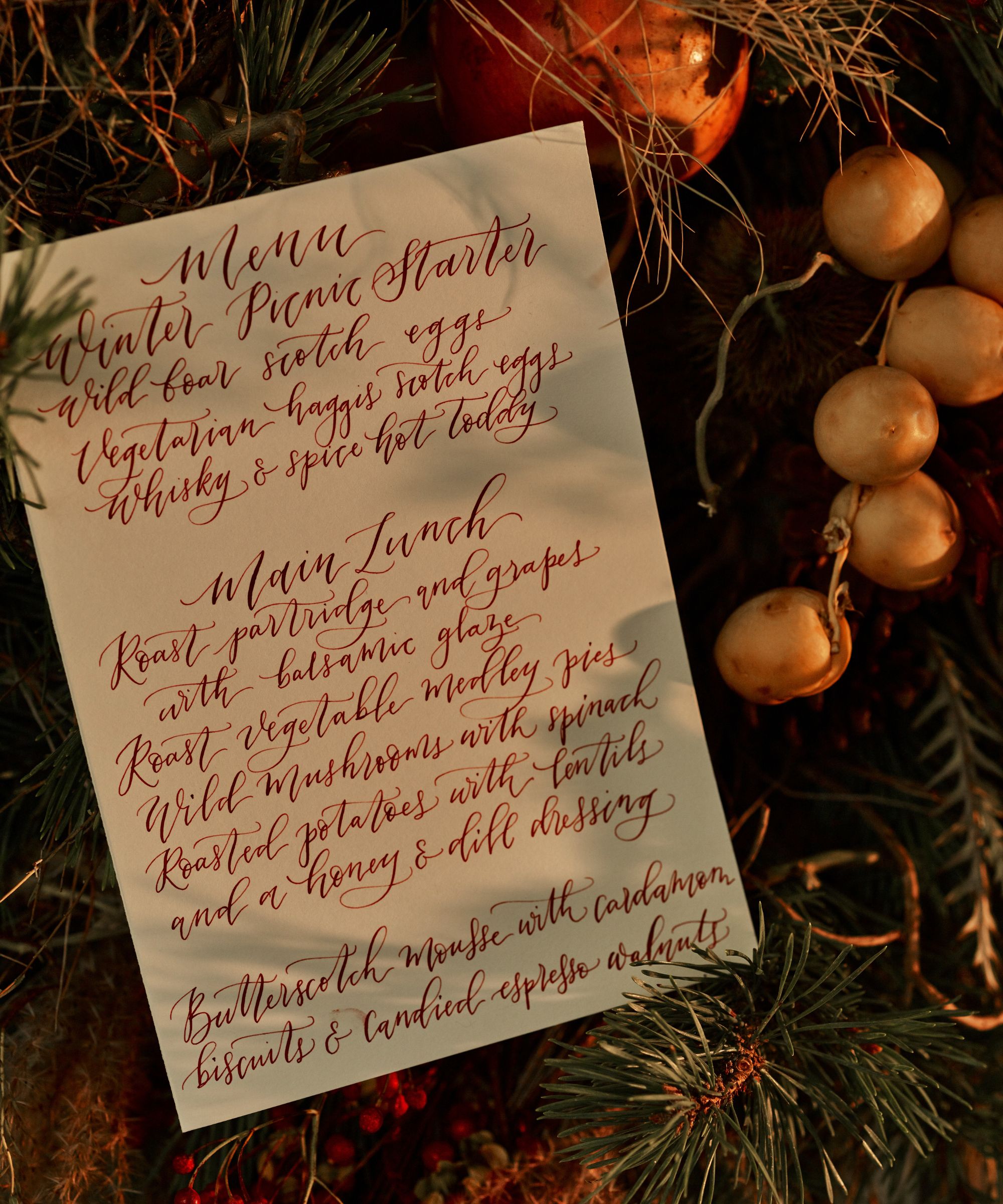 Handwritten dinner menu next to pine and berry wreath