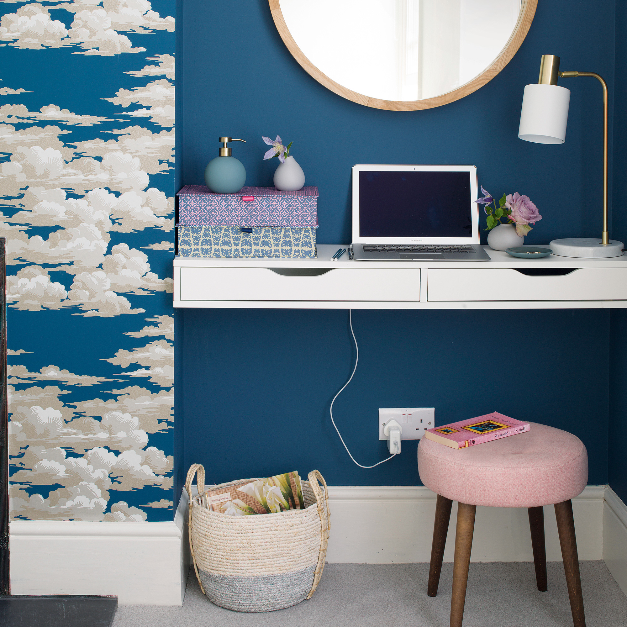 a blue and pink bedroom with a laptop open on the dressing table desk