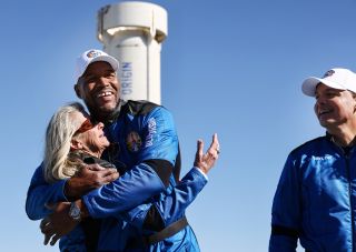 Good Morning America co-anchor and former NFL star Michael Strahan embraces Laura Shepard Churchley, daughter of astronaut Alan Shepard, as Dylan Taylor, Chairman & CEO of Voyager Space, looks on during a media availability on the landing pad after they flew into space aboard Blue Origin’s New Shepard on December 11, 2021 near Van Horn, Texas.